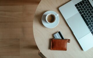stolik z filiżanką espresso, portfelem i laptopem